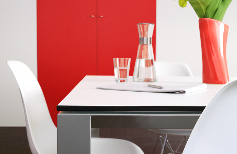 Une table à manger dont la surface est blanche, grâce au Compact de marque Formica® Blanc (949), et dotée de pattes grises qui mettent en valeur son design moderne.